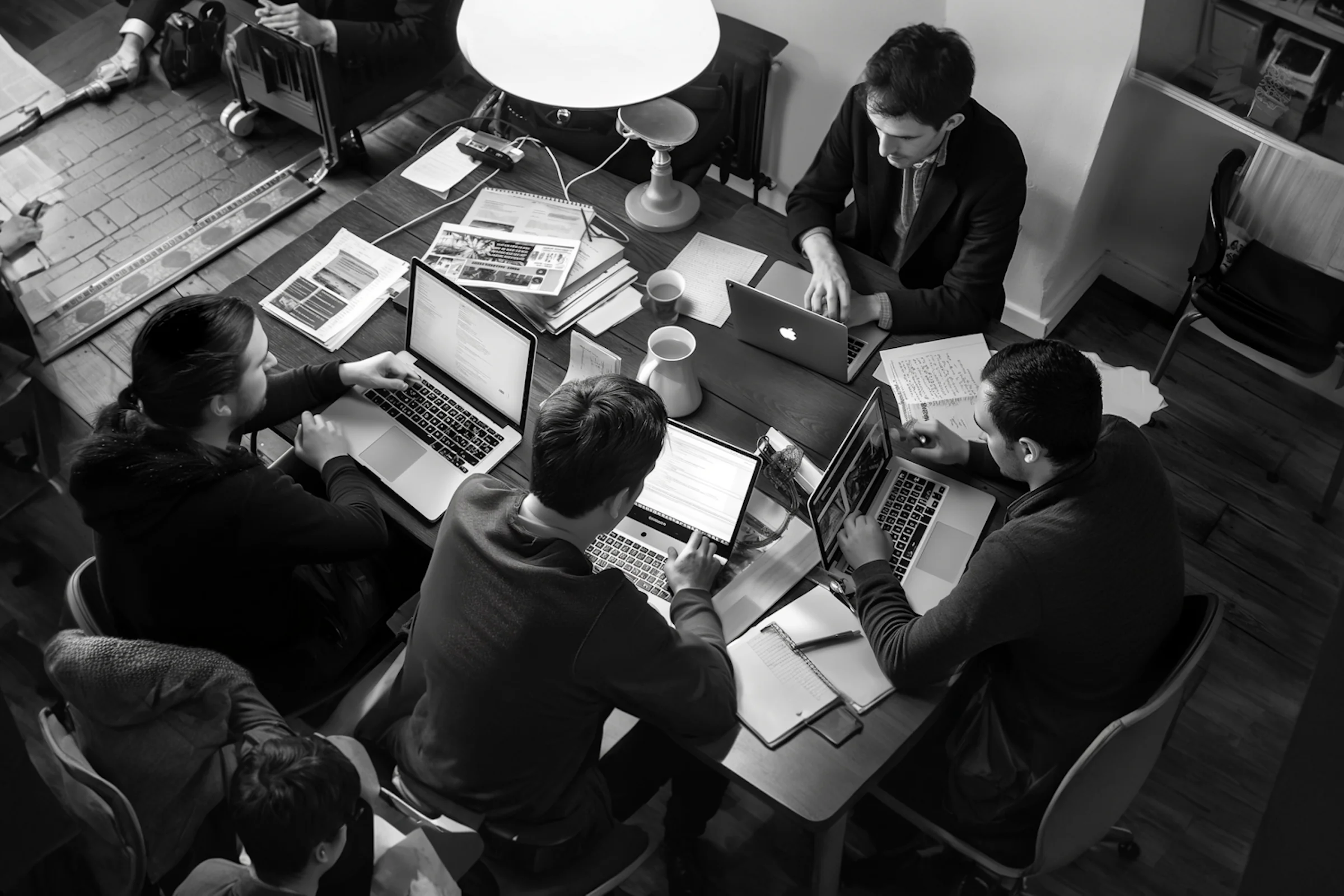 Black-and-white overhead view of a team working around a table